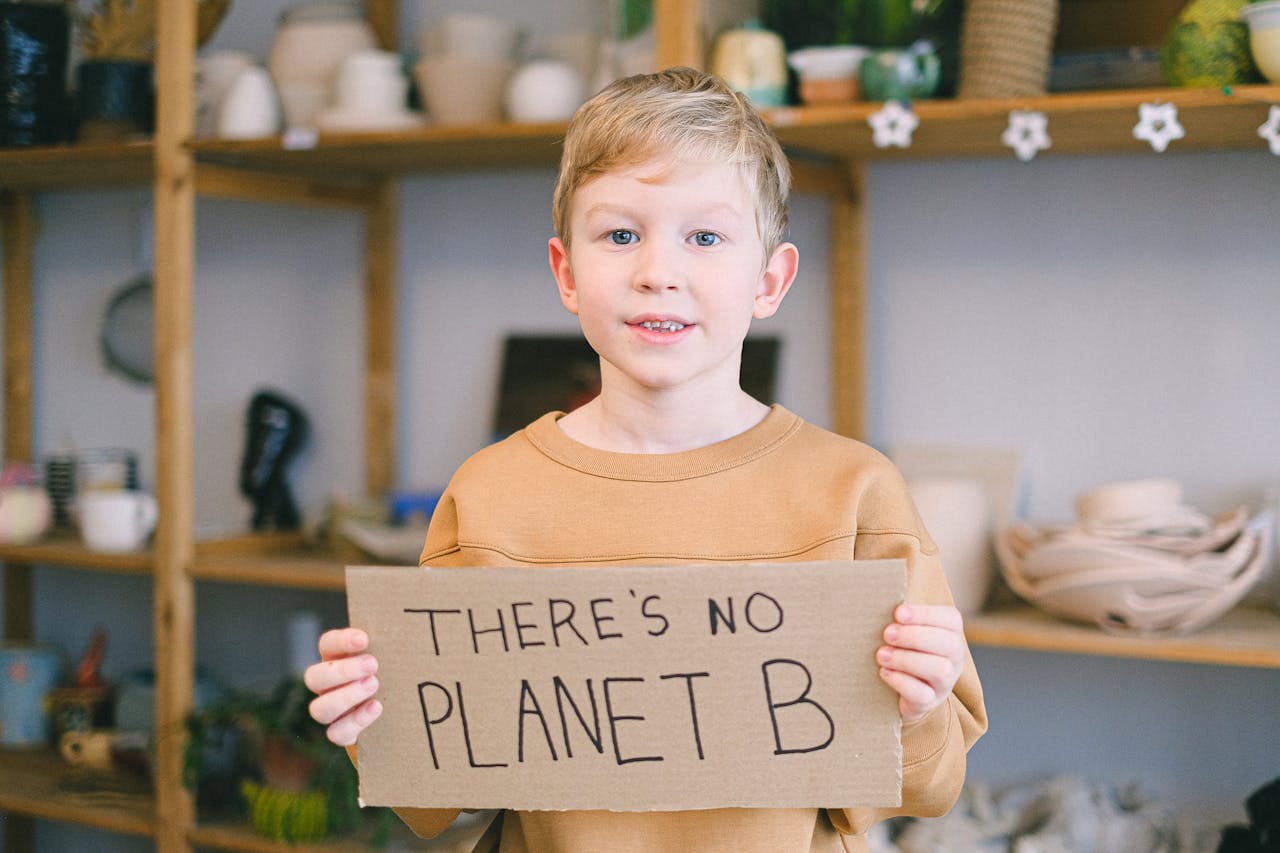 services-02 Young boy holding a sign saying 'There's No Planet B,' promoting environmental awareness.