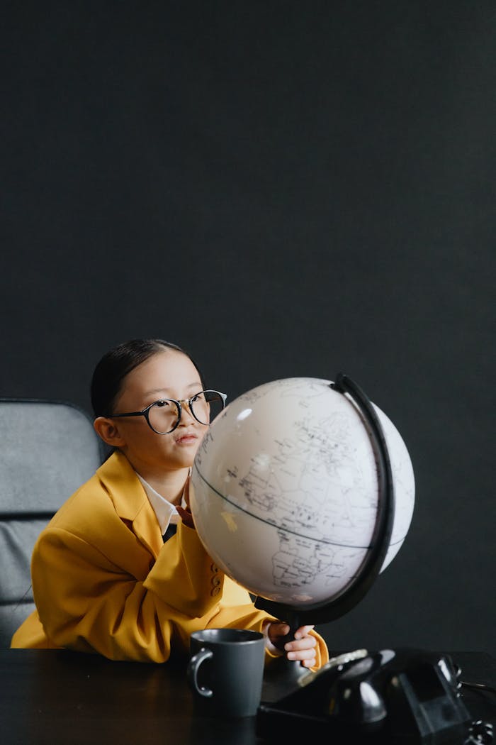 our-services-1 Curious child in glasses exploring a globe, fostering a love for geography.