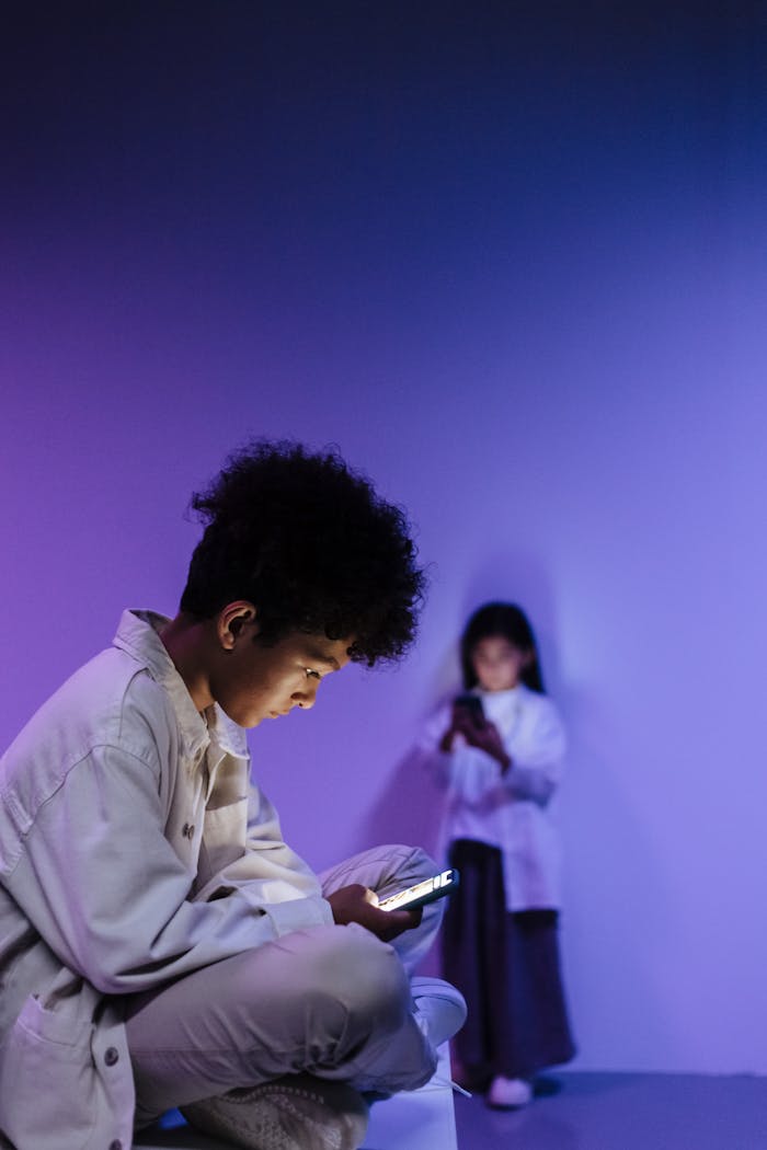 our-services-2 Two children with smartphones in a modern studio with colored lighting.